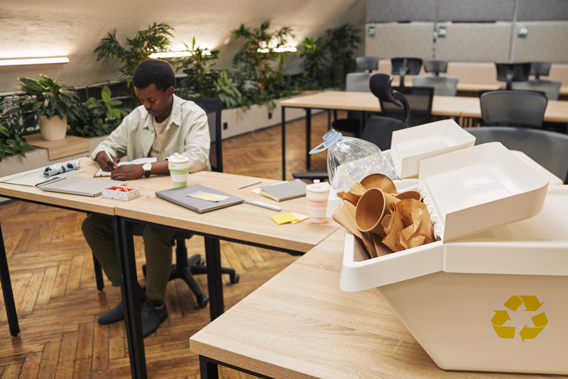 Bureau avec bac de tri sélectif et collaborateur au travail